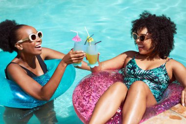 İki arkadaş havuzda keyifli keyifli kokteyller içiyor, şişme yüzüyorlar. Yüksek kalite fotoğraf