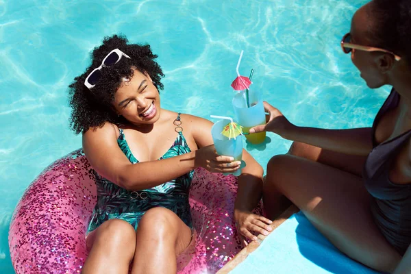 İki arkadaş havuzda keyifli keyifli kokteyller içiyor, şişme yüzüyorlar. Yüksek kalite fotoğraf
