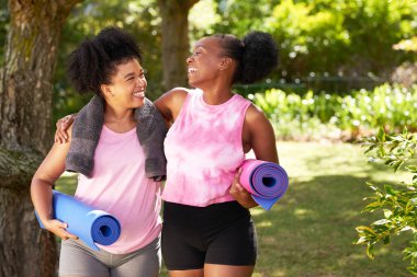 İki mutlu genç arkadaş parkta yoga seansından önce gülüp sarılıyor. Yüksek kalite fotoğraf