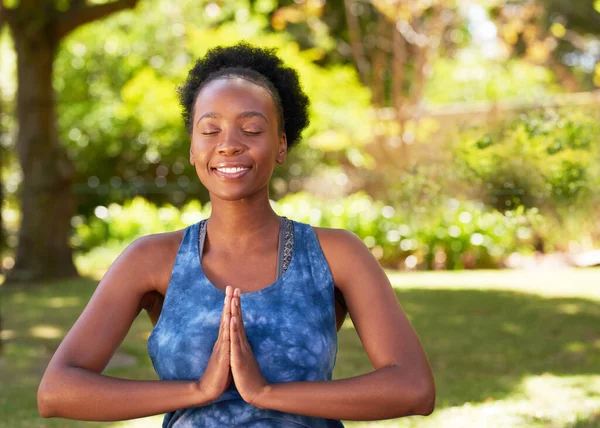 stock image Young Black woman sitting outdoors in yoga pose, hands in prayer meditating. High quality photo