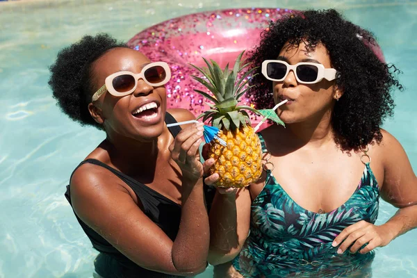 stock image Two Black friends drink a pineapple drink in the pool on summer vacation. High quality photo