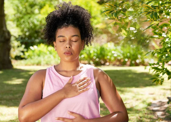 Genç ve etnik kadın derin nefes alma pratiği yapıyor, parkta meditasyon yapıyor. Yüksek kalite fotoğraf