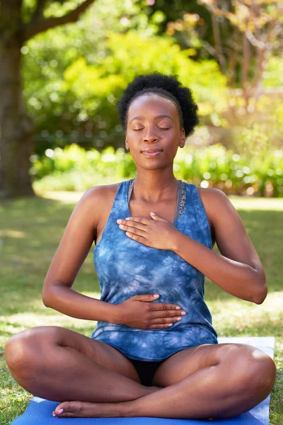 Young beautiful Black woman practices deep belly breathing on yoga mat outdoors. High quality photo