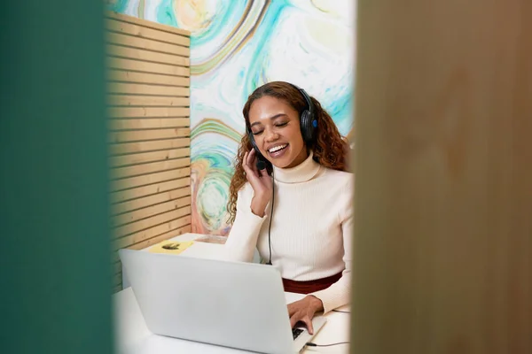 Shot of young office worker sitting in private booth, on remote call headset. High quality photo