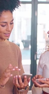 İki dost canlısı çok ırklı iş arkadaşı cep telefonu ekranını paylaşırken konuşuyor. Yüksek kaliteli FullHD görüntüler