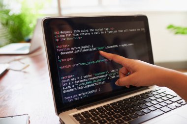 Young female developer points finger to laptop screen with javascript code . High quality photo clipart