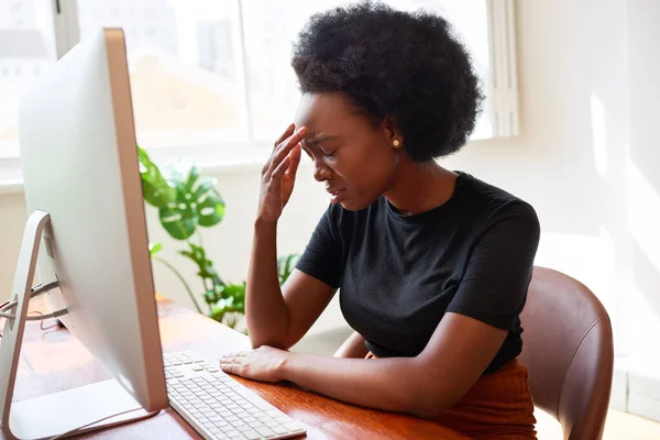 stock image Tired and upset young developer sits with head in hands at desk, Black woman. High quality photo