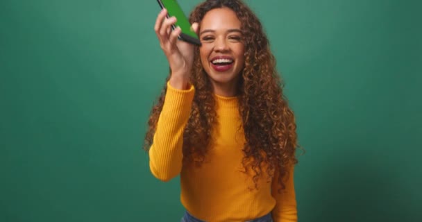 幸せな若い女性は デバイスのクロマキー画面 緑のスタジオの背景を保持しています 高品質の4K映像 — ストック動画