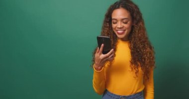 Mutlu genç kadın, yeşil stüdyo arka planında krom anahtar ekranı tutuyor. Yüksek kalite 4k görüntü