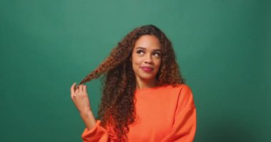 Güzel genç bir kadın flört ediyor ve kıvırıyor uzun kıvırcık saçlar, stüdyo geçmişi. Yüksek kalite 4k görüntü