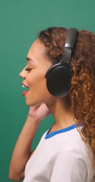 Молодая Многонациональная Женщина Слушает Музыку Наушниках Танцах Зеленой Студии Высококачественные — стоковое видео