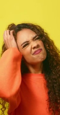 Genç, çok ırklı bir kadın, kafa karıştıran, düşünen ve kafası karışık, sarı bir stüdyo. Yüksek kalite 4k görüntü