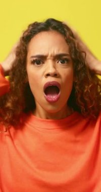 Şok olmuş ve üzgün genç bir kadın el ele tutuşuyor, sarı stüdyo geçmişi var. Yüksek kalite 4k görüntü