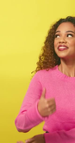 コピースペース 美しい多民族女性 黄色いスタジオを指す親指 高品質の4K映像 — ストック動画