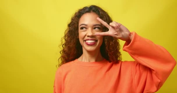 Glückliche Junge Frau Hält Friedenszeichen Auge Alberne Pose Gelbes Studioporträt — Stockvideo