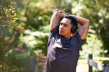 Ciddi bir Asyalı parkta ısınmak ve spor yapmak için kollarını havaya kaldırıyor. Yüksek kalite fotoğraf