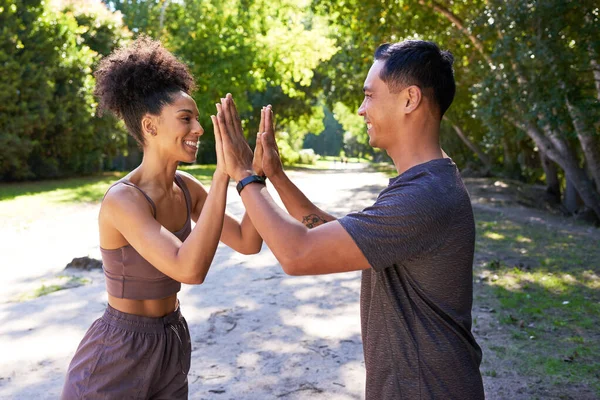 Beautiful fit couple give each other double high five after trail run outdoors. High quality photo