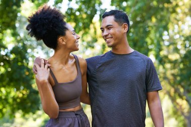 Çok ırklı güzel bir çift parkta birlikte egzersiz yapıyor, poz veriyor ve gülümsüyor. Yüksek kalite fotoğraf
