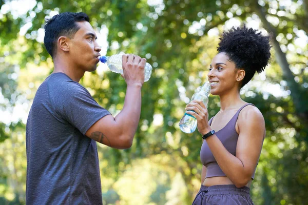 Fitness team cools down after exercise in park, beautiful couple drinking water . High quality photo