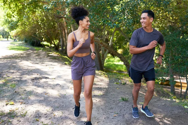 Fit couple runs together in park, trail running outdoors smiling and happy. High quality photo