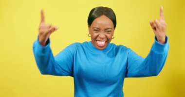 Genç siyahi kadın el işaretleri üzerinde taşla dans ediyor, gülüyor, sarı stüdyo. Yüksek kalite 4k görüntü