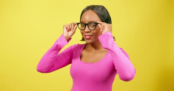 美しい黒人女性は 眼鏡を試して愚かな顔を引っ張ります 黄色のスタジオ 高品質の4K映像 — ストック動画