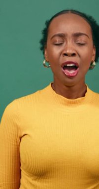 Genç siyahi kadın esniyor ve esniyor, yeşil arka plan stüdyo videosu. Yüksek kalite 4k görüntü
