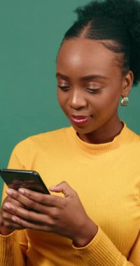 Güzel bir genç kadın cep telefonuyla mesajlaşıyor, gülümsüyor, yeşil stüdyo geçmişi var. Yüksek kalite 4k görüntü