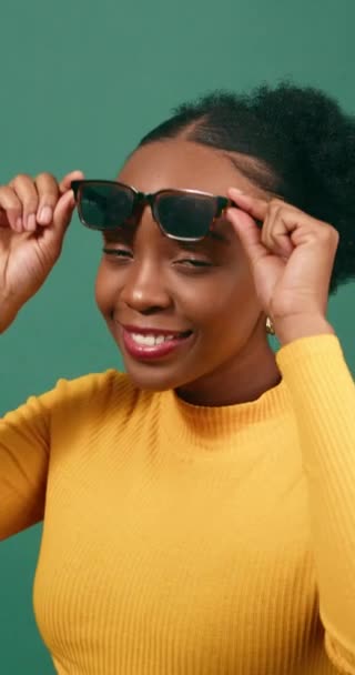 美しい若い女性はサングラスを持ち上げ 平和のサイン 緑のスタジオ 高品質の4K映像 — ストック動画