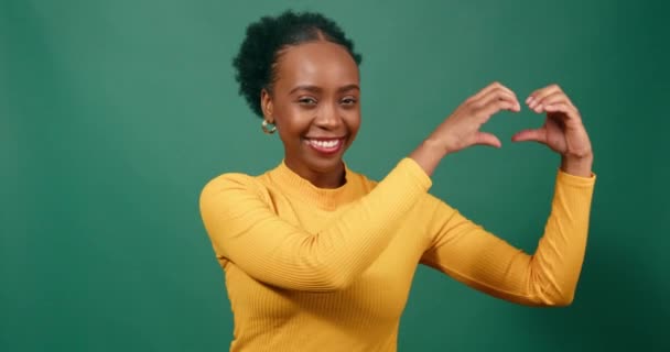 Молода Чорна Жінка Формує Серце Руками Усміхнений Зелений Студійний Фон — стокове відео