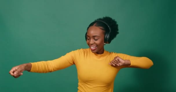 Młoda Czarna Kobieta Tańcząca Słuchawkami Zielone Tło Studia Wysokiej Jakości — Wideo stockowe