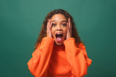 Mutlu, şaşkın ve çok ırklı, yeşil stüdyo geçmişi olan bir kadın. Yüksek kalite fotoğraf