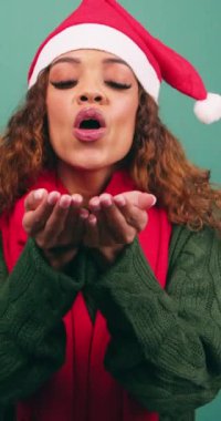 Güzel genç bir kadın yılbaşı stüdyosunda kameraya gökkuşağı konfetisi üflüyor. Yüksek kalite 4k görüntü