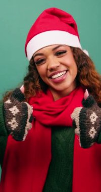 Gülümseyen, etnik çeşitlilikte genç bir kadın stüdyoda Noel renklerine onay veriyor. Yüksek kalite 4k görüntü