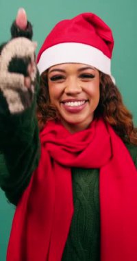 Gülümseyen, etnik çeşitlilikte genç bir kadın stüdyoda Noel renklerine onay veriyor. Yüksek kalite 4k görüntü