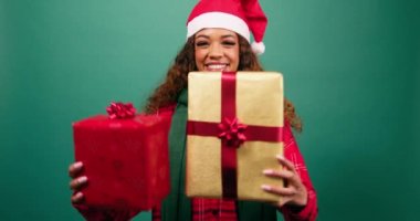 Mutlu genç kadın kameraya ve stüdyoya iki Noel hediyesi tutuyor. Yüksek kalite 4k görüntü