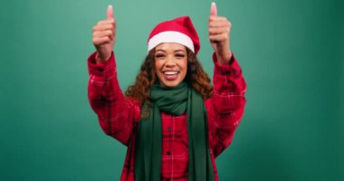 Gülümseyen, etnik çeşitlilikte genç bir kadın stüdyoda Noel renklerine onay veriyor. Yüksek kalite 4k görüntü