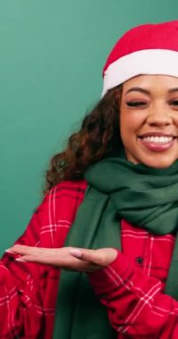 Güzel genç bayan, Noel Baba şapkası stüdyosu için sol tarafı işaret ediyor. Yüksek kalite 4k görüntü