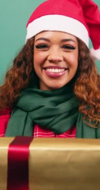 Mutlu genç kadın Noel hediyesini kameraya, stüdyoya doğru tutuyor. Yüksek kalite 4k görüntü