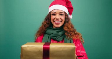 Mutlu genç kadın Noel hediyesini kameraya, stüdyoya doğru tutuyor. Yüksek kalite 4k görüntü