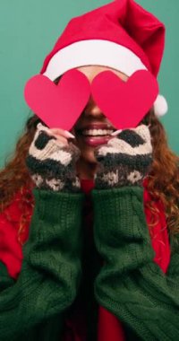 Güzel genç bir kadın, gözleri kalp şekilleriyle kaplıyor, Noel zamanı aşkla. Yüksek kalite 4k görüntü