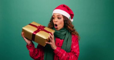 Heyecanlı genç kadın Noel hediyesini sallıyor, içinde ne olduğunu tahmin et, Stüdyo. Yüksek kalite 4k görüntü