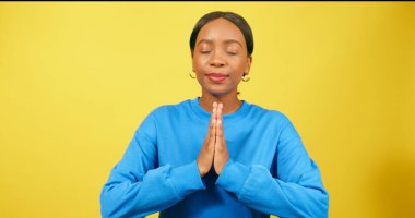 Sakin genç kadın ellerini dua pozisyonuna koyar, dua eder, sarı stüdyo. Yüksek kalite fotoğraf