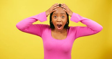 Şok olmuş ve heyecanlı genç bir kadın el ele tutuşuyor, sarı stüdyo geçmişi var. Yüksek kalite fotoğraf