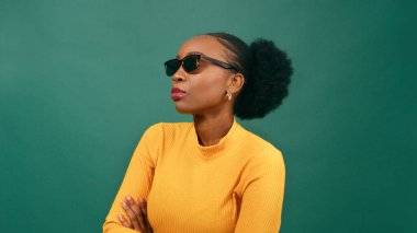 Güneş gözlüklü, kollarını kavuşturmuş, yeşil atölyeli güzel bir bayan. Yüksek kalite fotoğraf