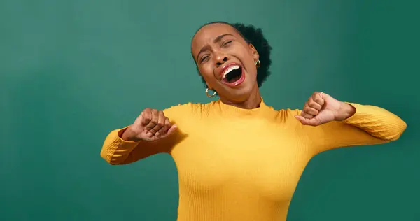 Young Black woman yawns and stretches, green background studio video. High quality photo