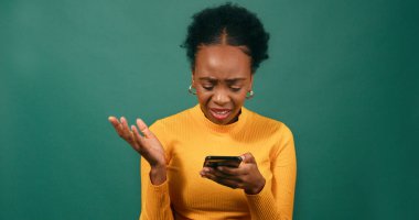 Genç bir kadın, üzgün ve kafası karışmış bir şekilde yeşil stüdyo geçmişi olan kısa mesajlar okur. Yüksek kalite fotoğraf