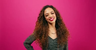 Mutlu genç bayan pembe stüdyoda gülüyor, randevu gecesinde giyinmiş. Yüksek kalite 4k görüntü