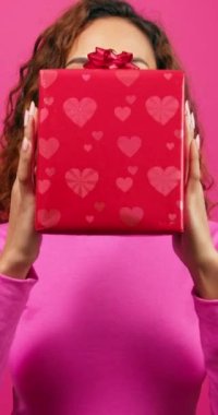 Heyecanlı genç bir kadın hediye kutusunu tutuyor ve yüzünü, pembe kurdelesini, yıldönümünü gösteriyor. Yüksek kalite 4k görüntü