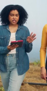 Yürüyen ve konuşan iki kadın çiftçi dijital tablet ile veri analizini tartışıyor. Yüksek kalite 4k görüntü